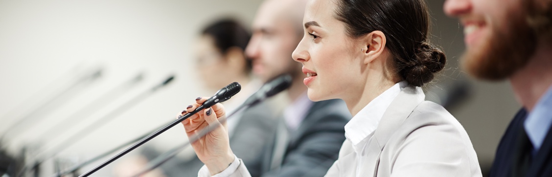 Lady speaking into a microphone at a Conference