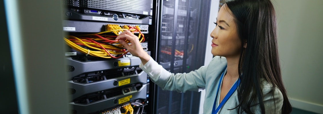 Woman looking at server rack and adjusting cables